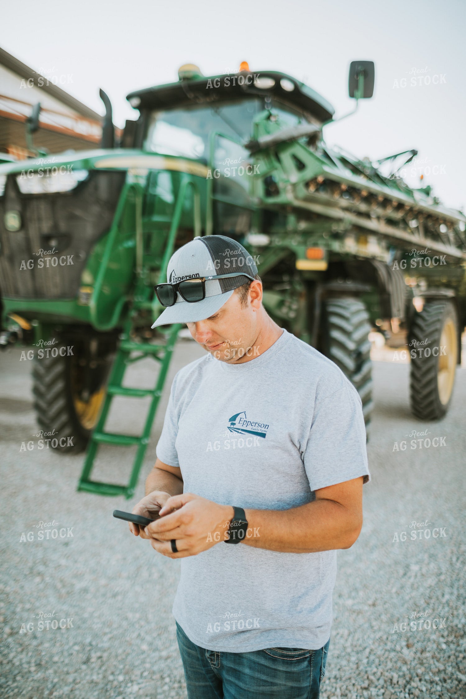 Farmer Looking at Phone with Sprayer in Background 6251