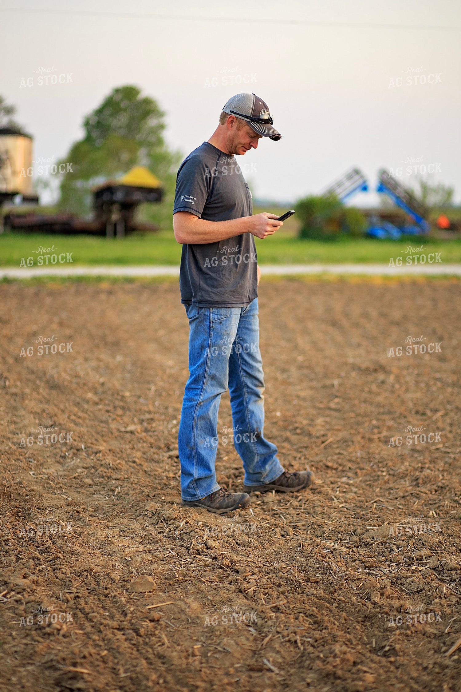 Farmer Looks at Phone in Field 93211