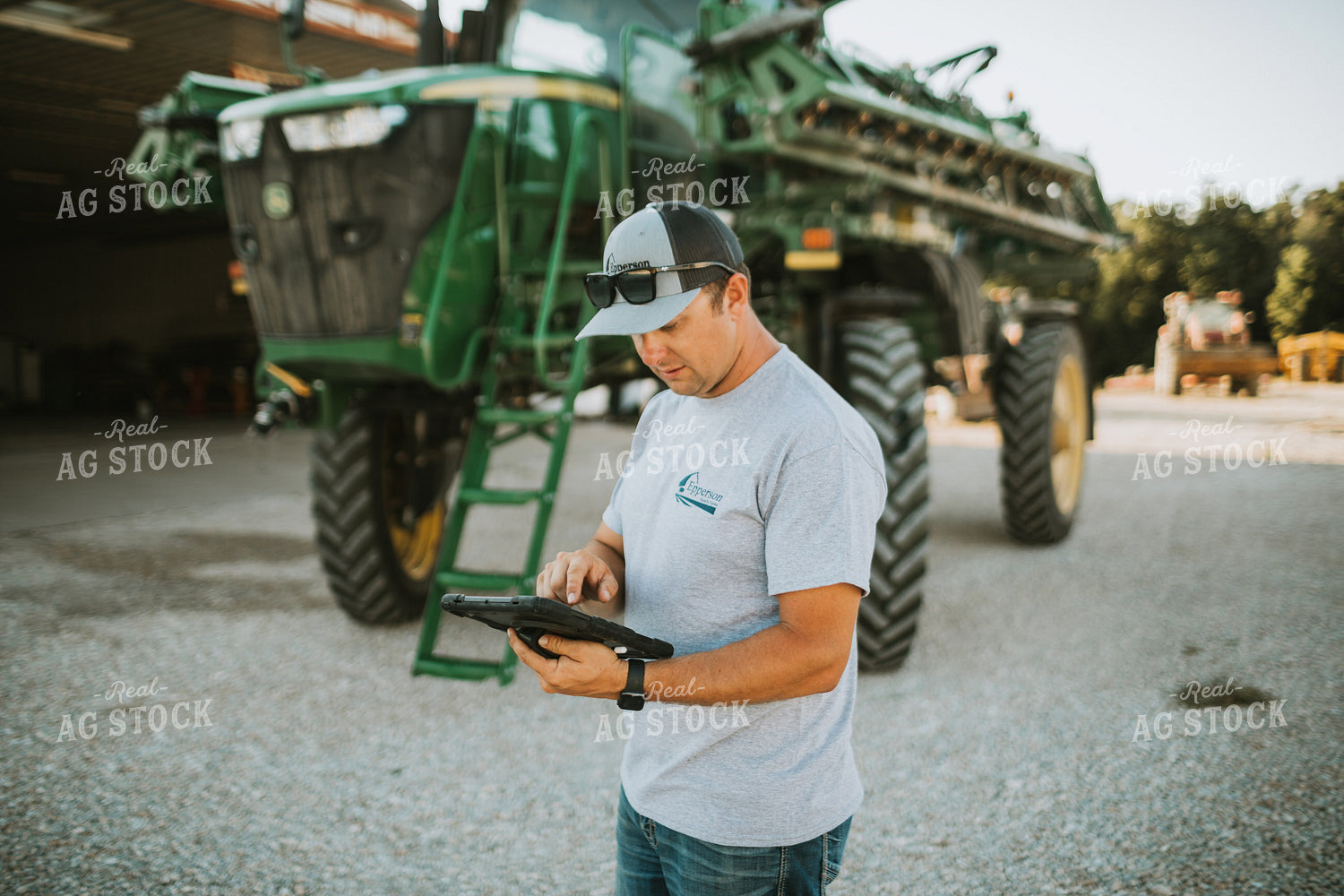 Farmer Looking at iPad with Sprayer in Background 6247