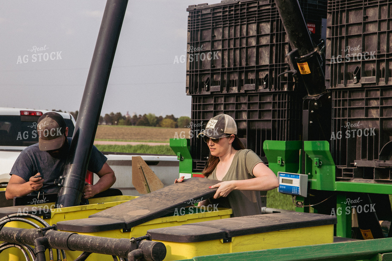 Male and Female Farmers Load Planter Boxes with Seed Tender 67306