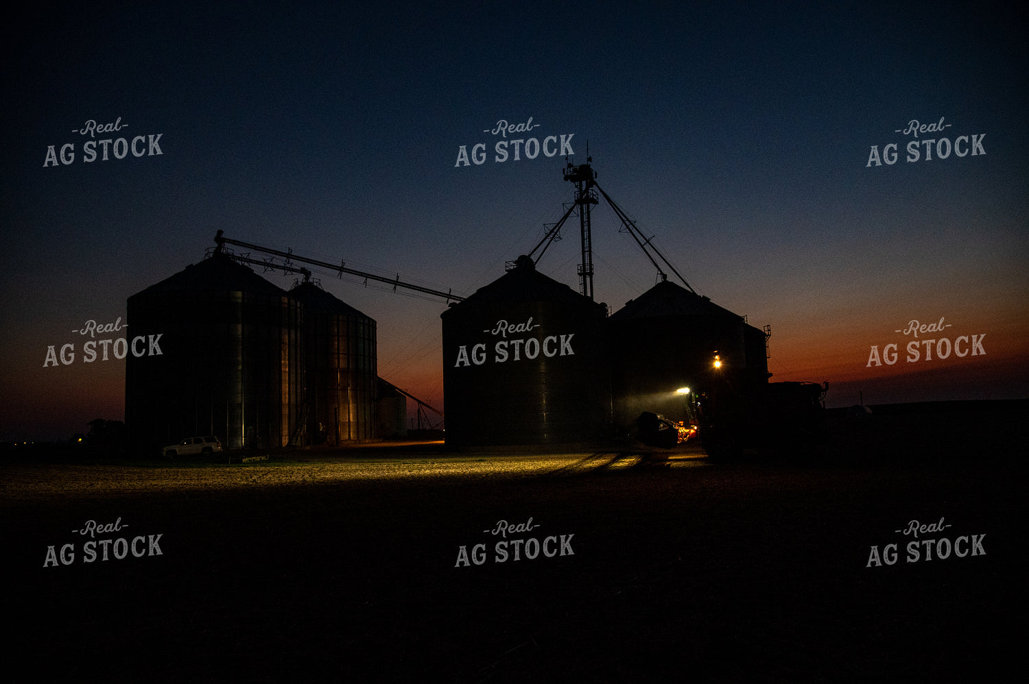 Combine Parked in Front of Grain Bin Site after Sunset 25800