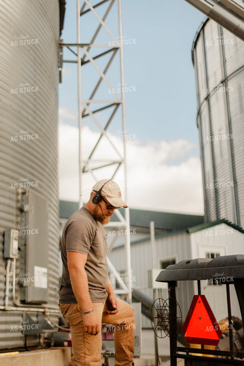 Farmer Talking on Headset by Grain Bins 9347