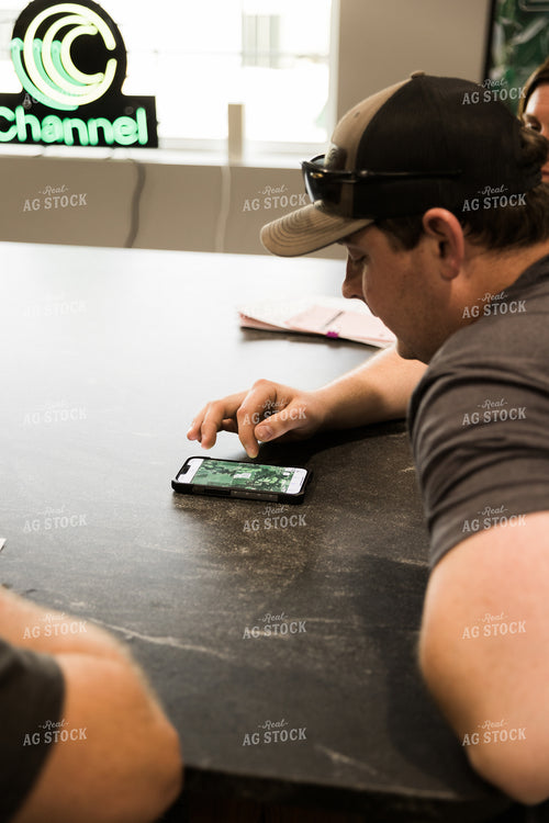 Farmers Look at Aerial View of Farmland on Phone in Office 7621