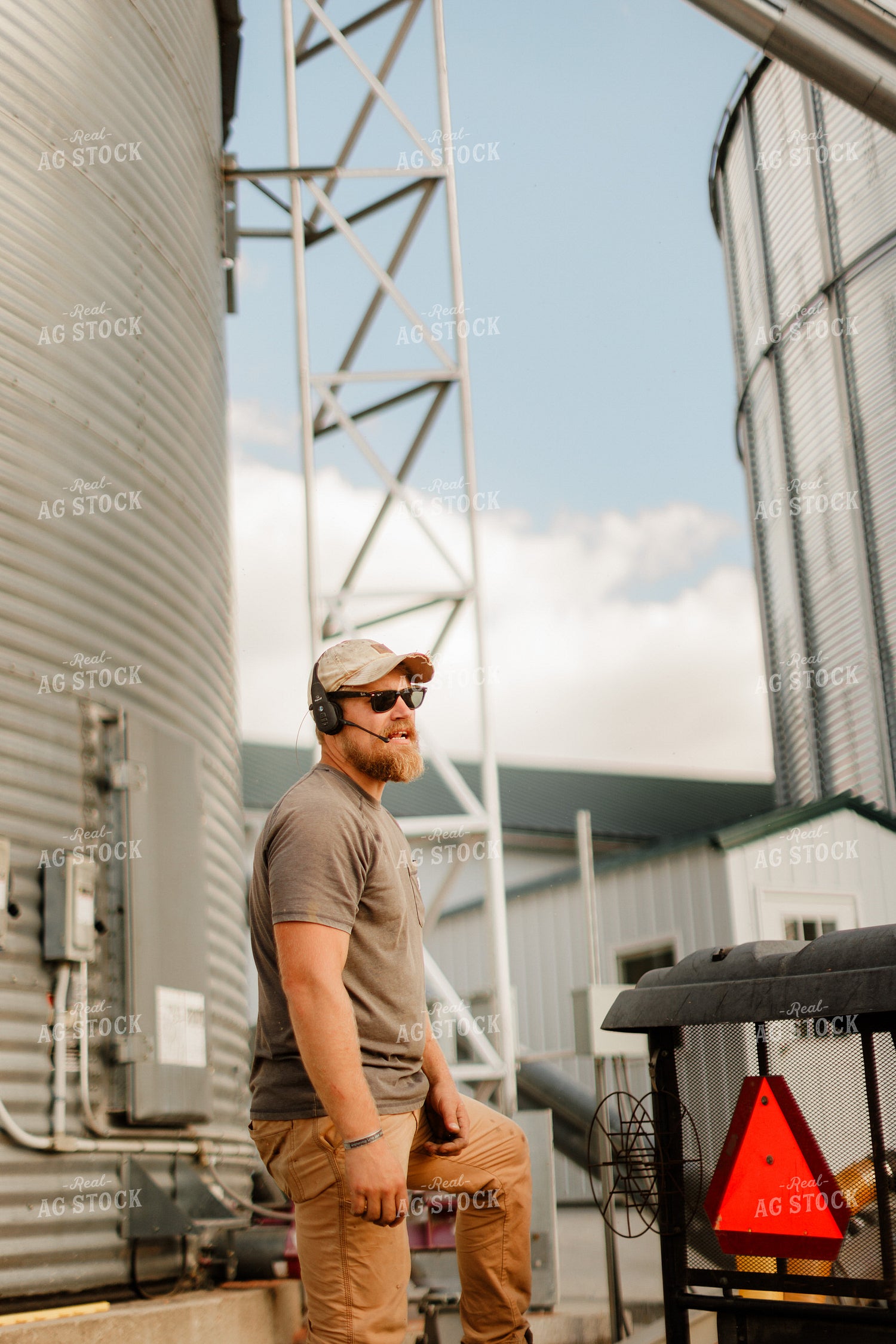 Farmer Talking on Headset by Grain Bins 9346