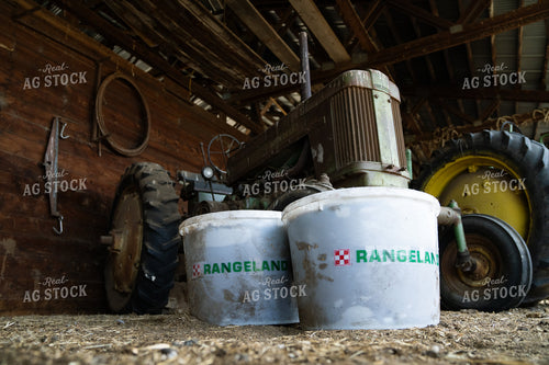 Rural Farm Scene with Tractor and Rangeland Buckets Inside a Wooden Barn 65258