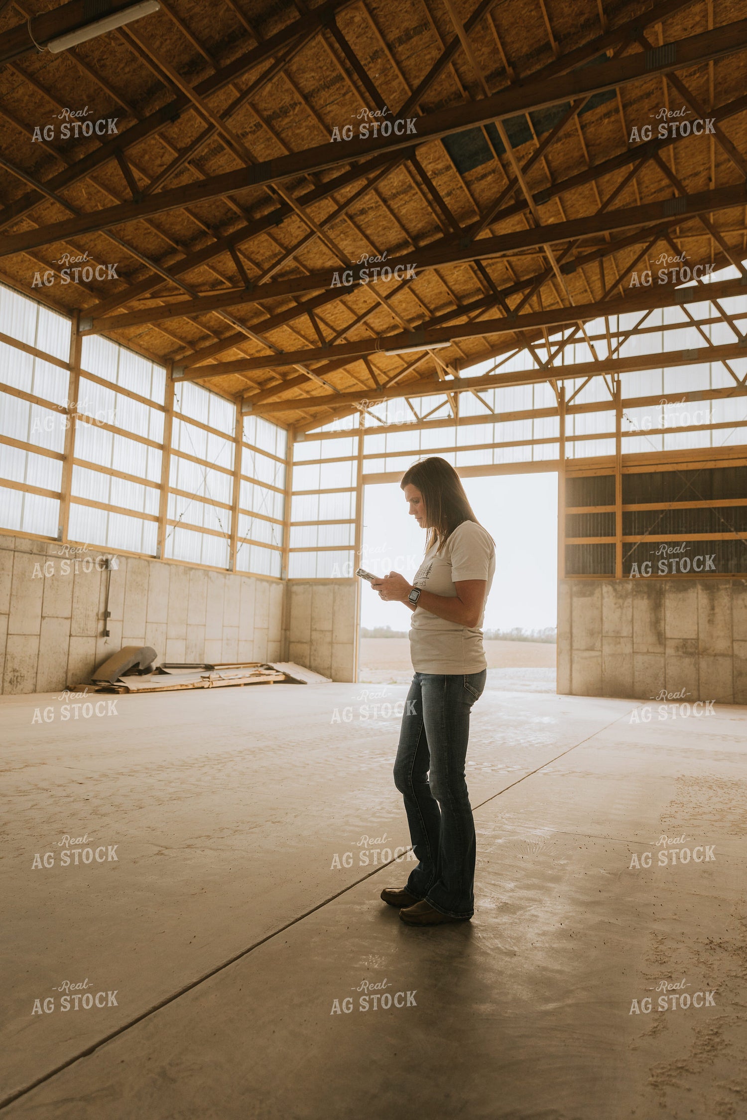 Woman Farmer Looks at Phone in Shed 7538