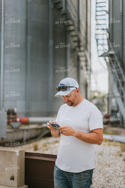 Farmer Looking at Phone by Grain Bin 8764