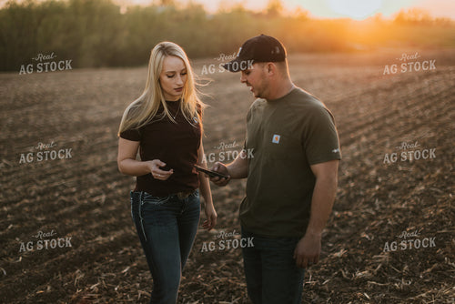Young Couple Look at Phone in Field at Sunset 7728