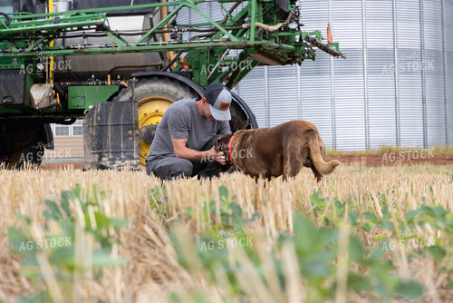 Farmer Bonding with Dog in Front of Agricultural Equipment 79699