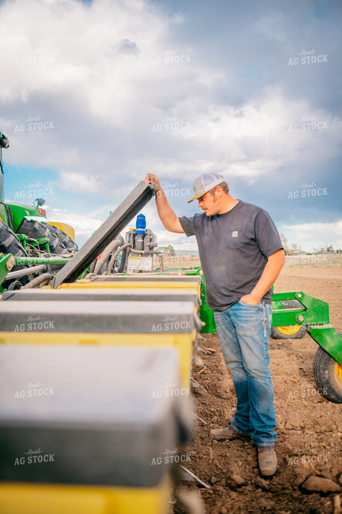 Farmer Opens Seed Hopper in Field During Planting 56654