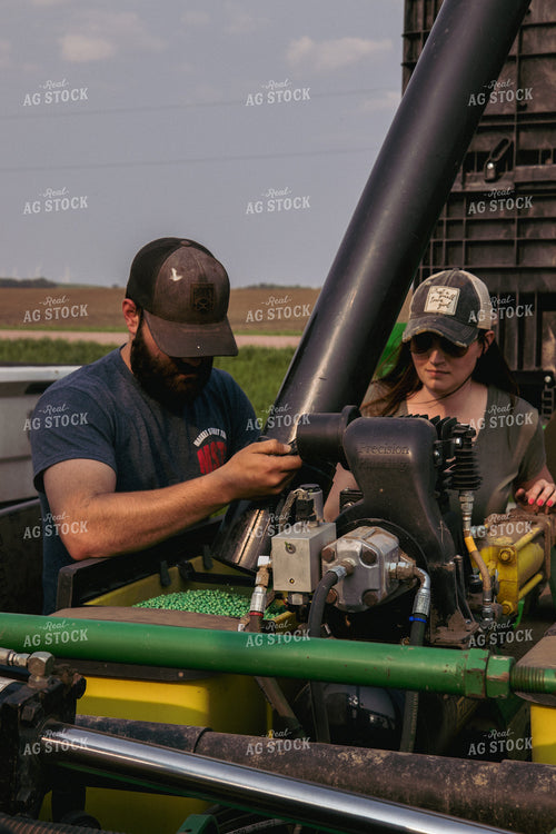 Male and Female Farmers Load Planter Boxes with Seed Tender 67309
