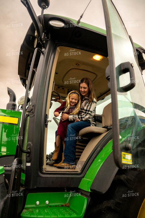 Female Farmer and Daughter Climbing out of Tractor 115419