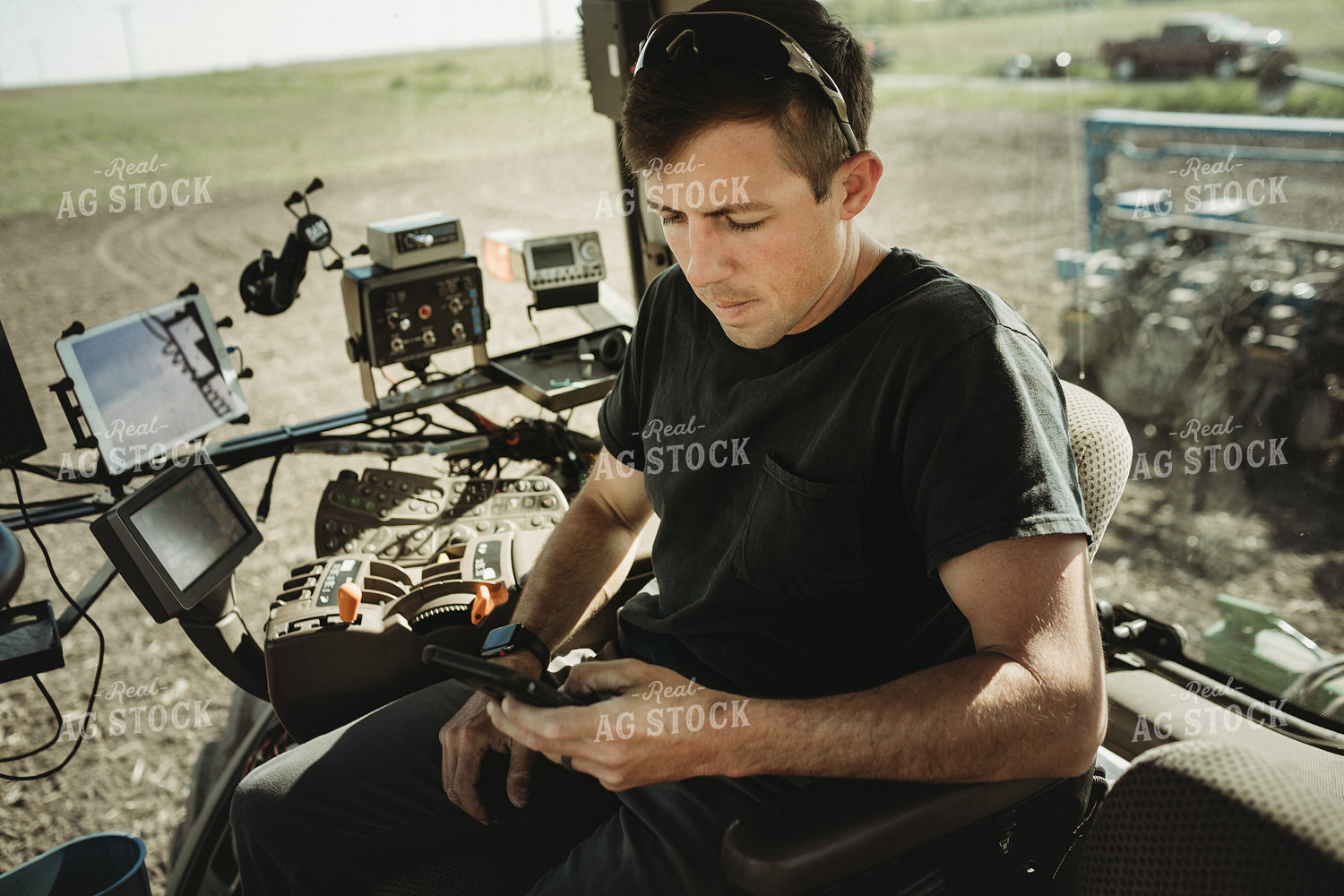 Farmer Looking at Phone in Tractor Cab 4119