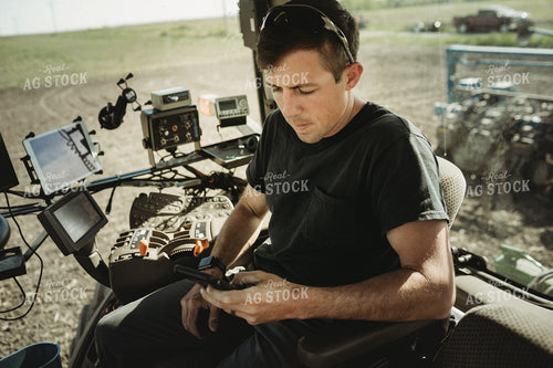 Farmer Looking at Phone in Tractor Cab 4119
