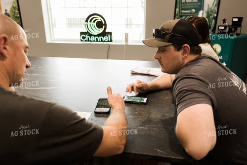 Farmers Look at Aerial View of Farmland on Phone in Office 7623