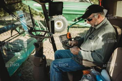Farmer Looking at Phone in Combine Cab 5228
