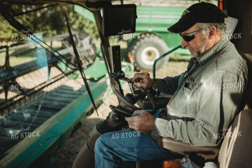 Farmer Looking at Phone in Combine Cab 5229