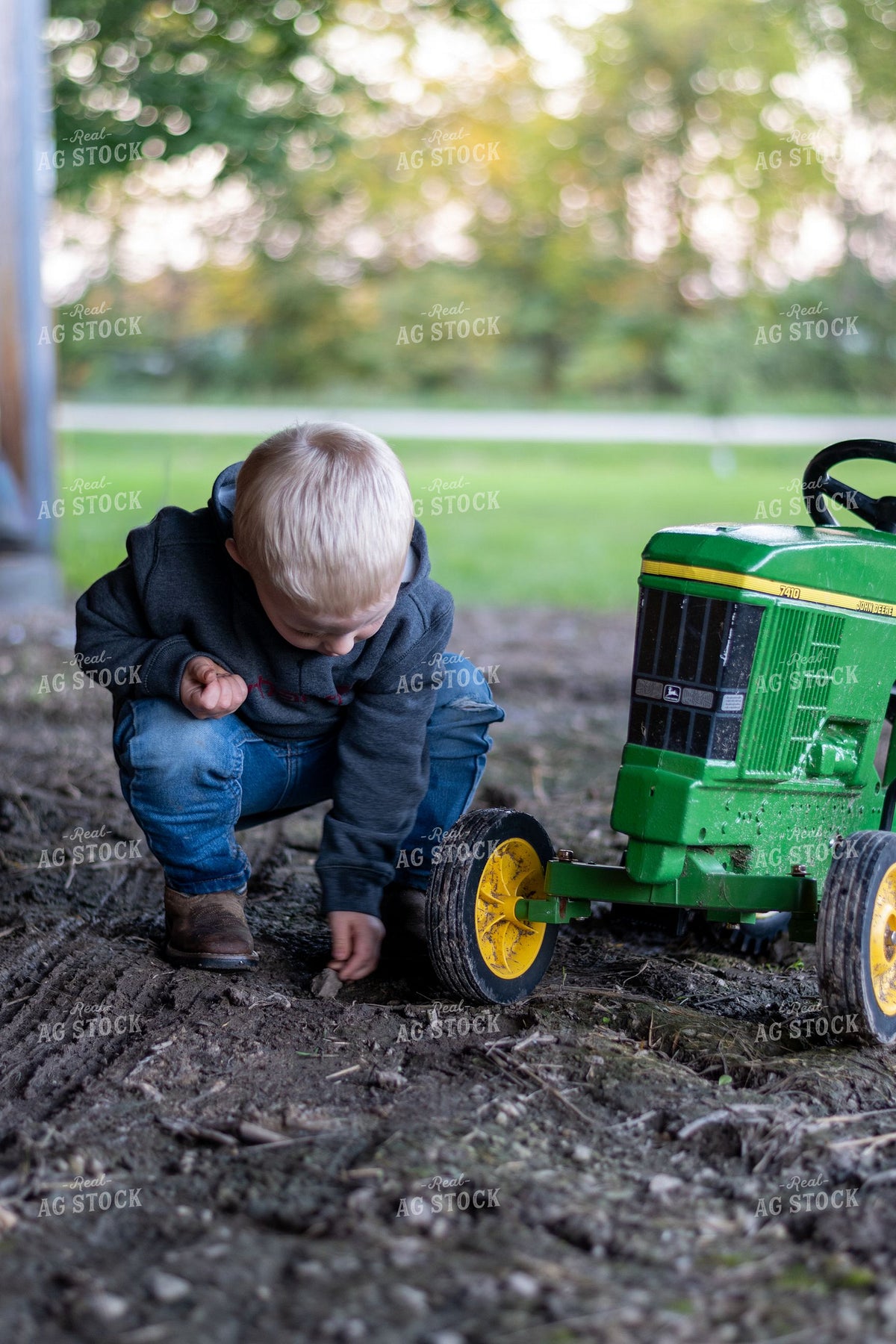 Young Farm Boy Playing with John Deere Toy Tractor in the Dirt 418000