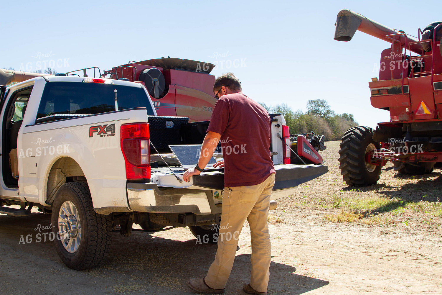 Farmer on Computer on Tailgate of Truck 79158