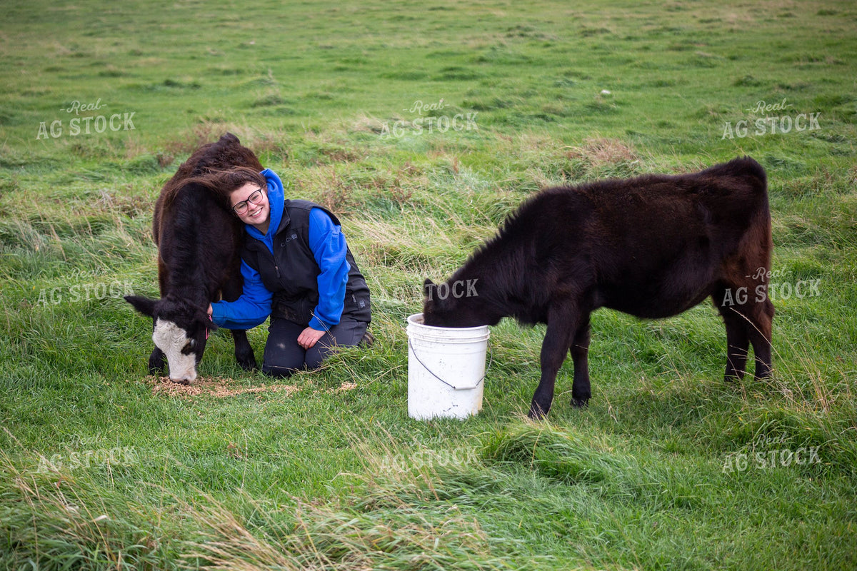 Young Female Rancher Feeding Calves in Green Pasture 406102