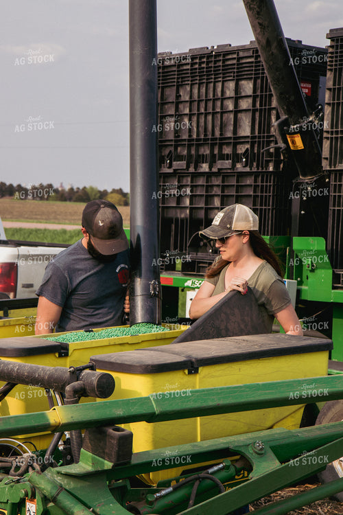 Male and Female Farmers Load Planter Boxes with Seed Tender 67305