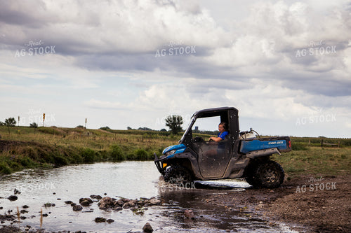 Farmer Driving Side by Side in Creek 67470