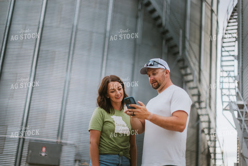 Farmer & Farm Wife Looking at Phone by Grain Bin 8770