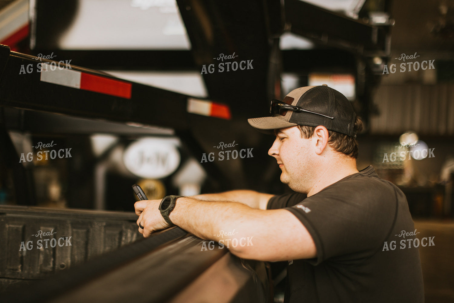 Farmer Looks at Phone While Leaning on Truck Bed 7575