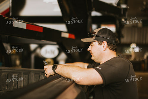 Farmer Looks at Phone While Leaning on Truck Bed 7575