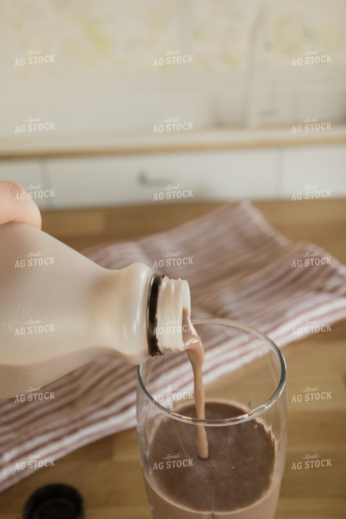 Chocolate Milk Pouring into Glass on Kitchen Countertop 67331