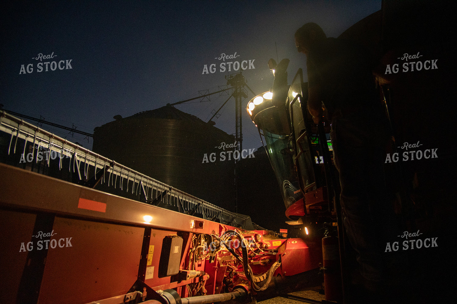 Farmer Climbing into Combine in Front of Grain Bin Site after Sunset 25801