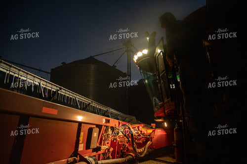Farmer Climbing into Combine in Front of Grain Bin Site after Sunset 25801