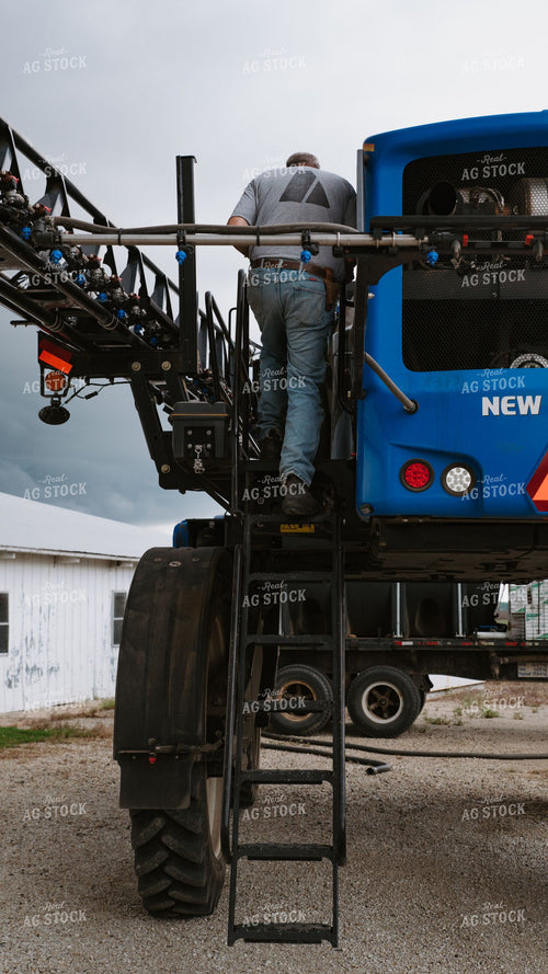 Farmer Climbing New Holland Self-Propelled Sprayer for Maintenance Inspection 401025