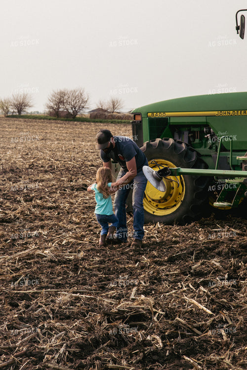 Father Picks up Daughter by Tractor in Freshly Planted Field 67297