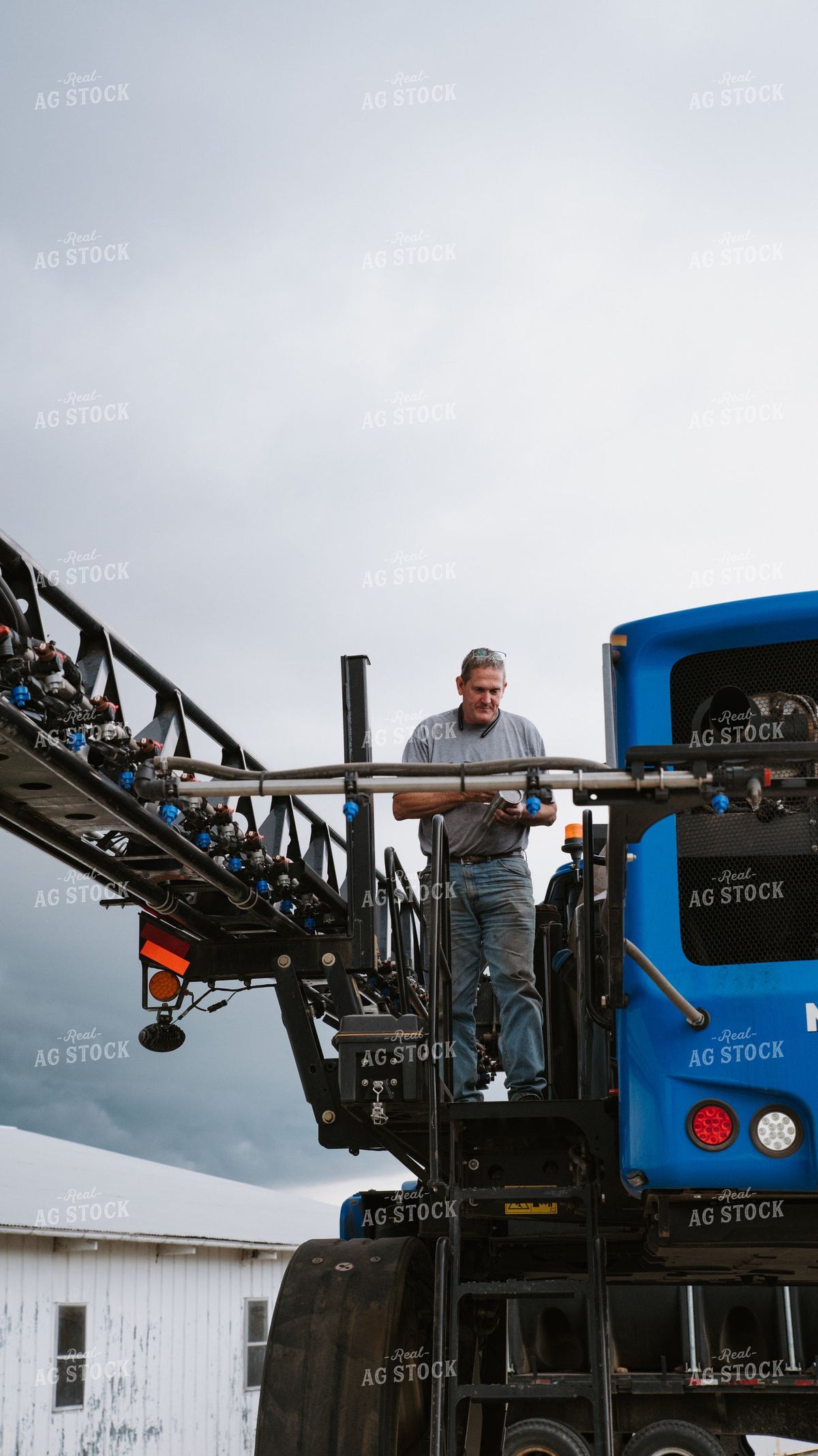 Applicator Inspecting Self-Propelled Sprayer Boom on Overcast Day 401005