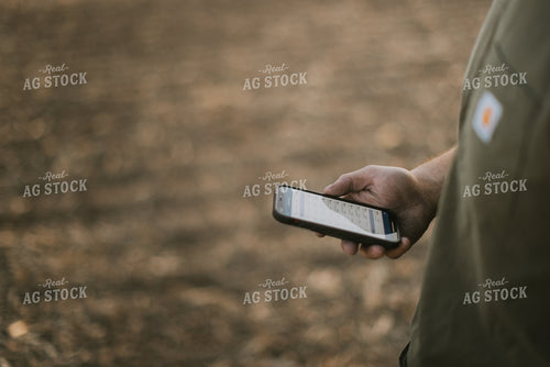 Young Farmer Looks at Phone in Field at Sunset 7732