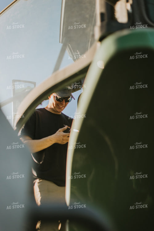 Young Farmer Looks at Phone While Climbing Tractor Ladder 7647