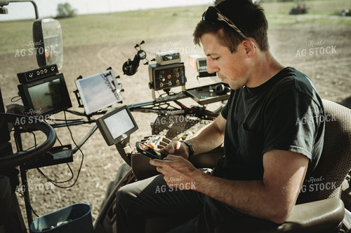 Farmer Looking at Phone in Tractor Cab 4118