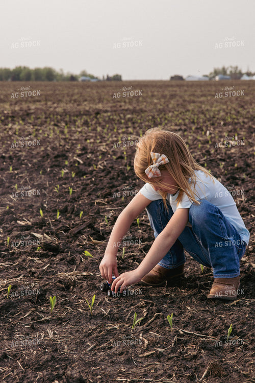 Farm Kid Plays with Toy Tractor in Emerging Corn Field 67291