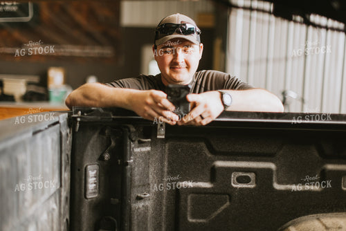 Farmer Looks at Phone While Leaning on Truck Bed 7574