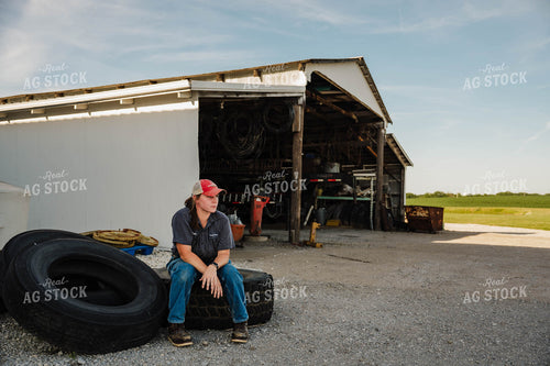 Female Farmer Sitting on Tires 115243