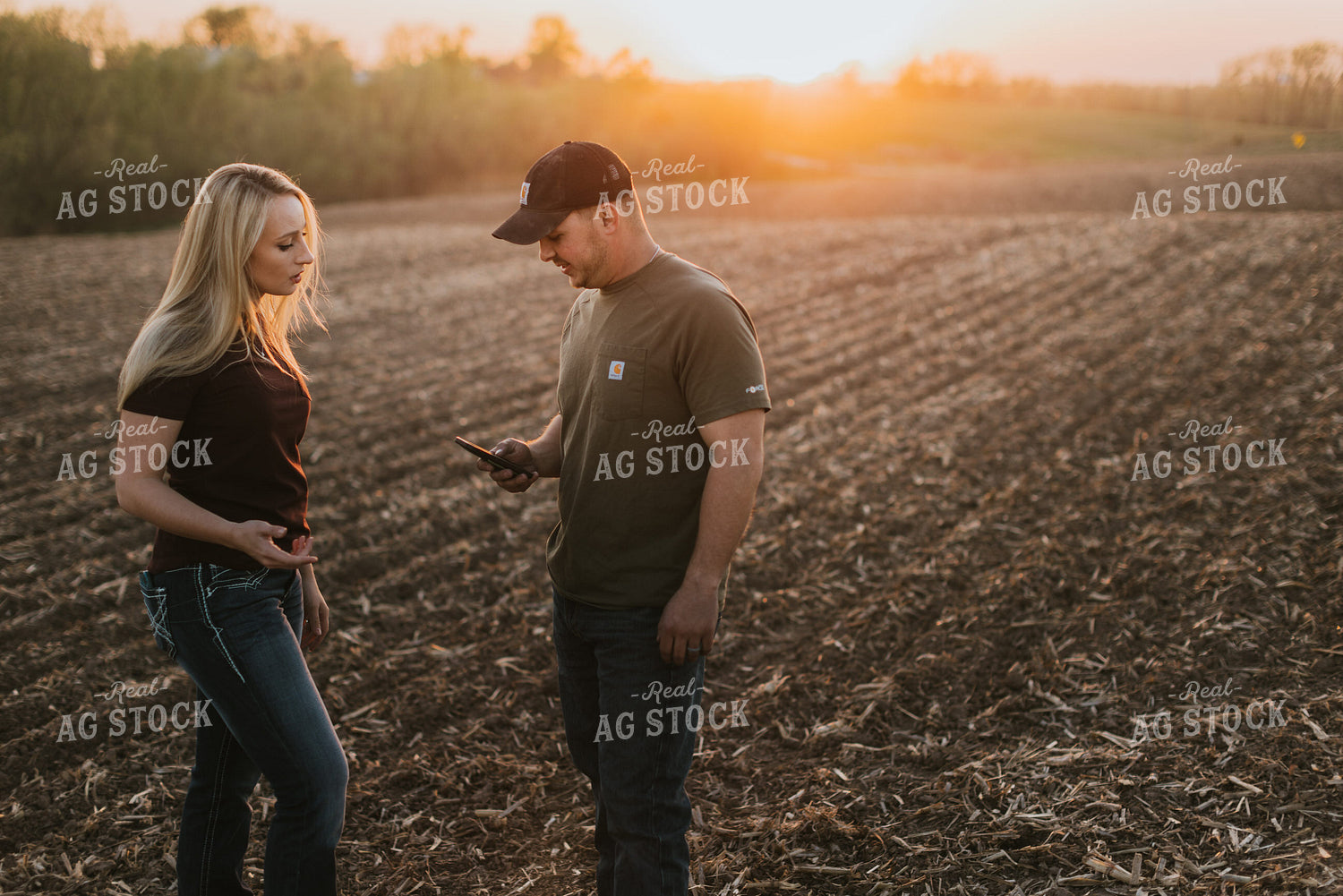 Young Couple Look at Phone in Field at Sunset 7727