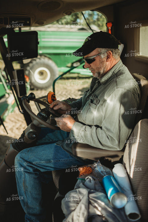 Farmer Looking at Phone in Combine Cab 5230