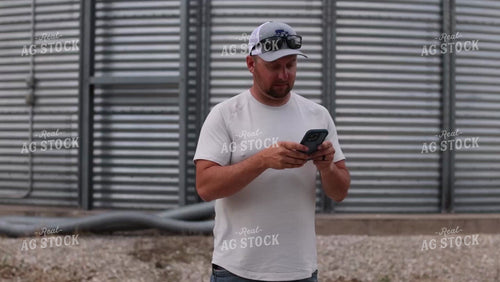 Farmer Looking at Phone by Grain Bin 9171