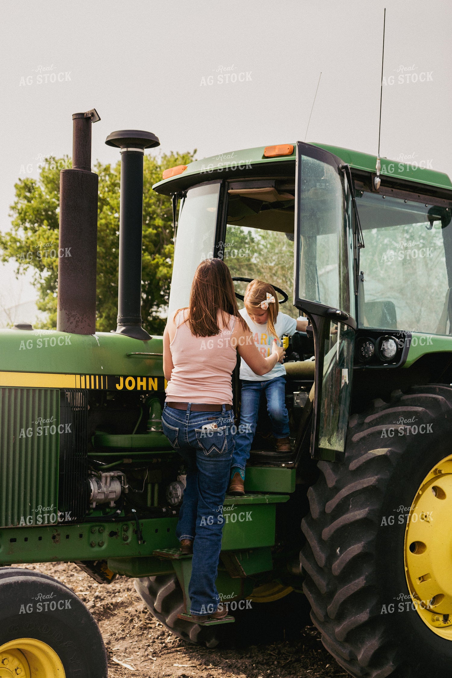Female Farmer Helps Daughter Down Tractor Ladder 67284