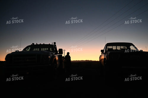 Farmer Standing by Trucks at Sunset 253009