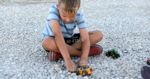 Farm Kid Playing with Toy Tractors in Gravel 6505
