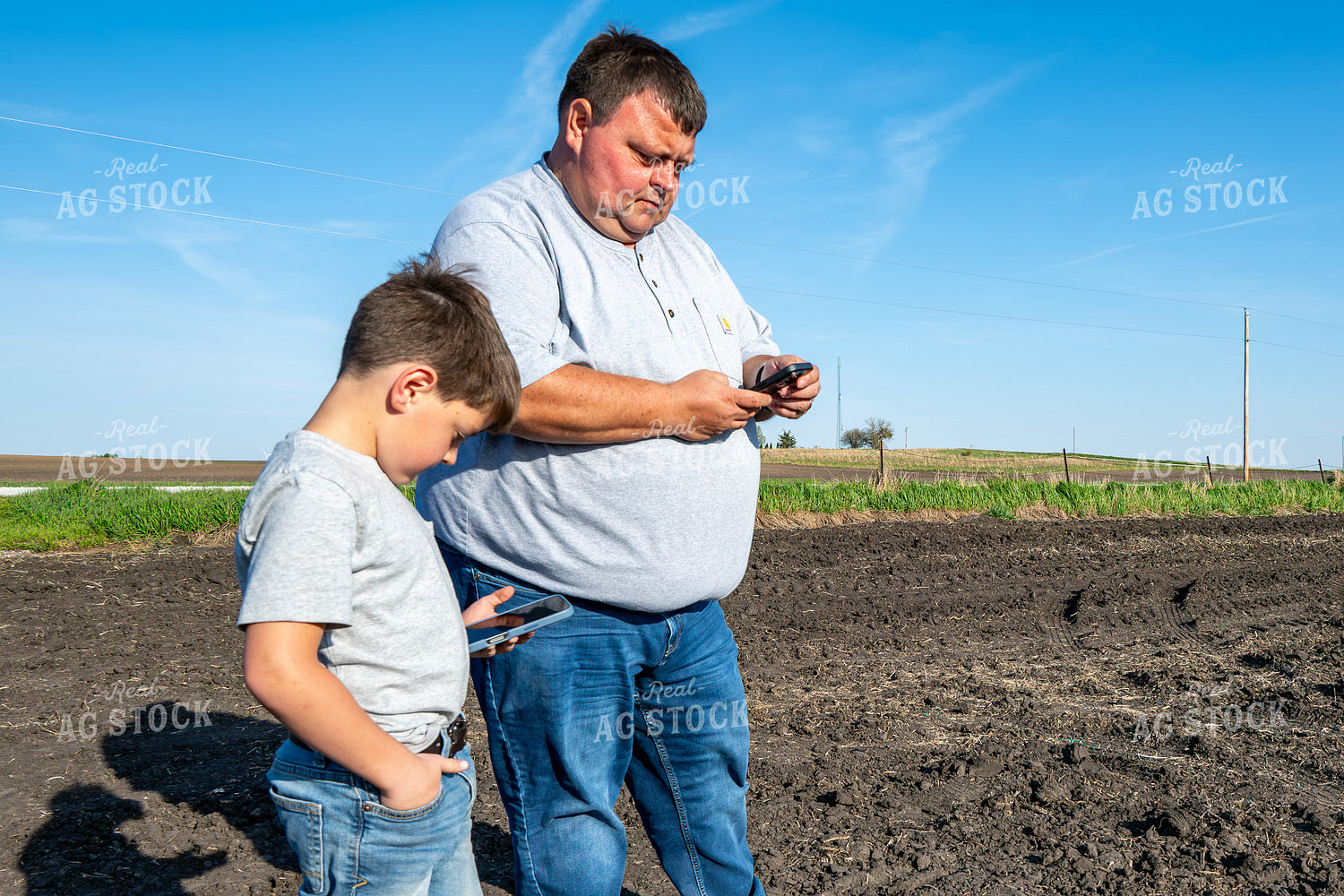 Farmer and Farm Kid Checking Phones in Field 302018