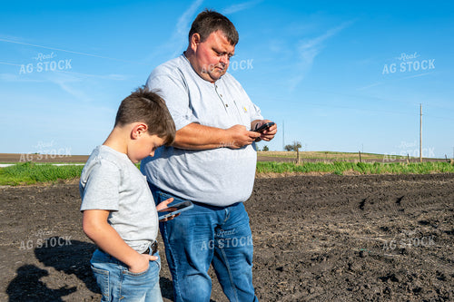 Farmer and Farm Kid Checking Phones in Field 302018