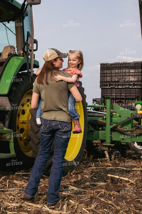 Female Farmer Holds Children in Field by Tractor and Planter 67300